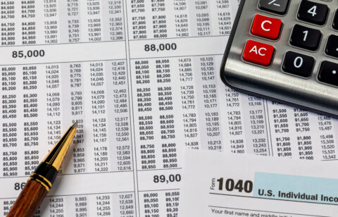 Close-up of tax documents with a calculator and pen, including a visible IRS Form 1040