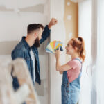 Couple choosing paint color samples while renovating a room in their home, smiling as they plan a home improvement project.