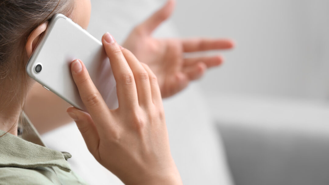 Close-up of a woman talking on a smartphone and gesturing with her hand during a phone conversation.