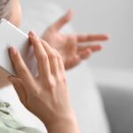 Close-up of a woman talking on a smartphone and gesturing with her hand during a phone conversation.