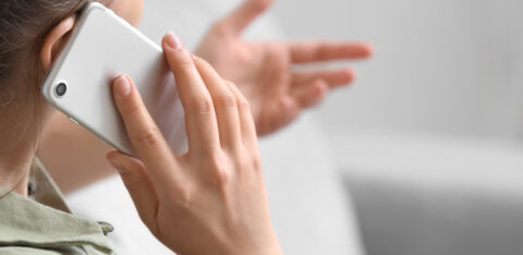 Close-up of a woman talking on a smartphone and gesturing with her hand during a phone conversation.