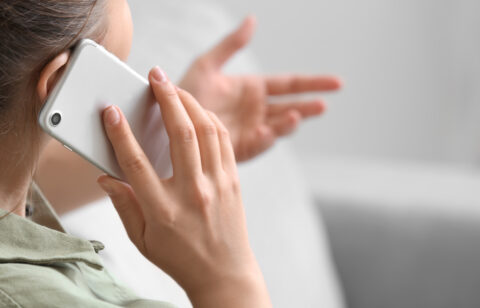 Close-up of a woman talking on a smartphone and gesturing with her hand during a phone conversation.