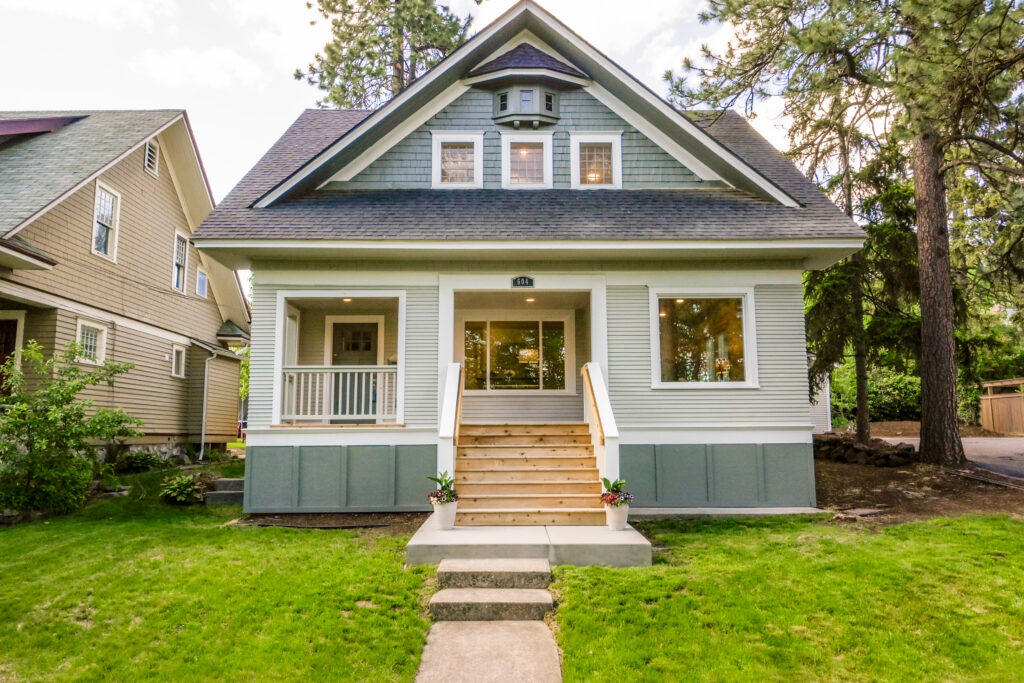 Front exterior of a two-story single-family home with a covered porch, front steps, and a landscaped lawn.