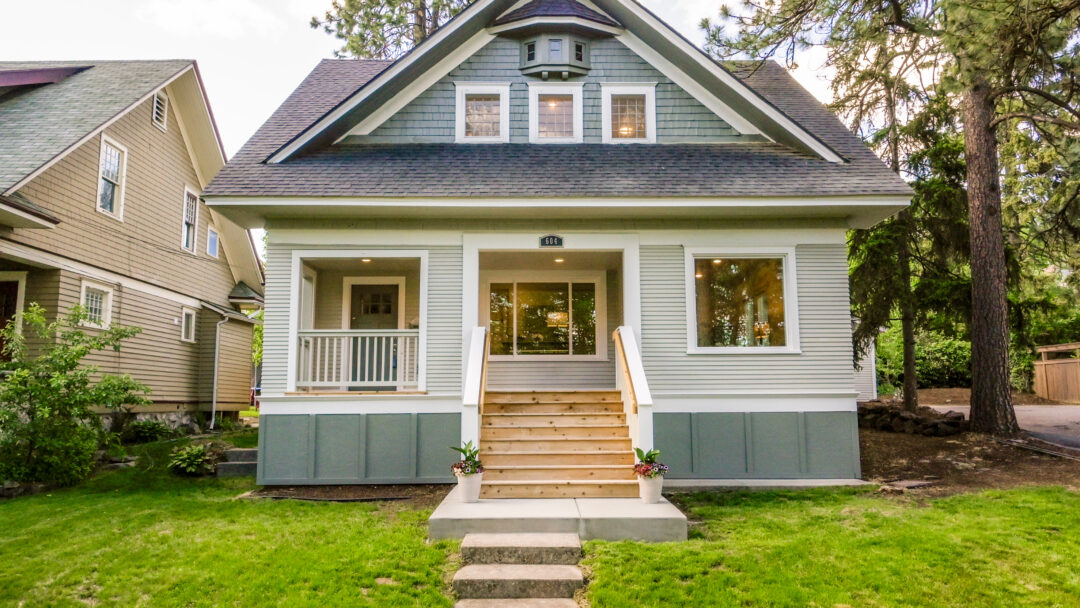 Front exterior of a two-story single-family home with a covered porch, front steps, and a landscaped lawn.