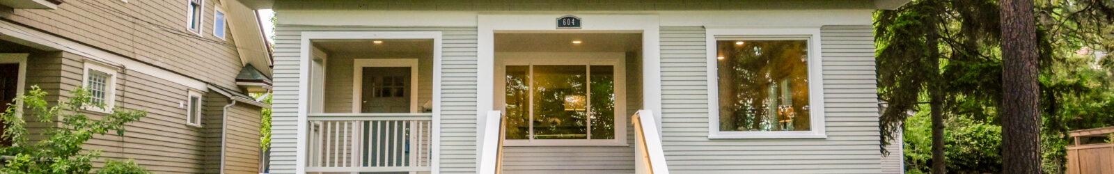 Front exterior of a two-story single-family home with a covered porch, front steps, and a landscaped lawn.