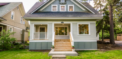 Front exterior of a two-story single-family home with a covered porch, front steps, and a landscaped lawn.
