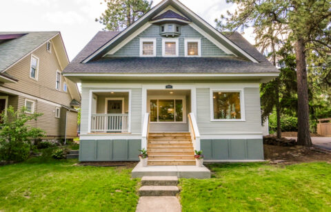 Front exterior of a two-story single-family home with a covered porch, front steps, and a landscaped lawn.