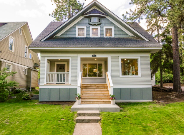 Front exterior of a two-story single-family home with a covered porch, front steps, and a landscaped lawn.