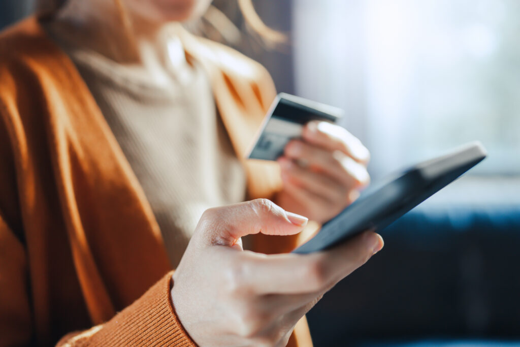 Woman holding a credit card and smartphone while making an online purchase or managing her finances.
