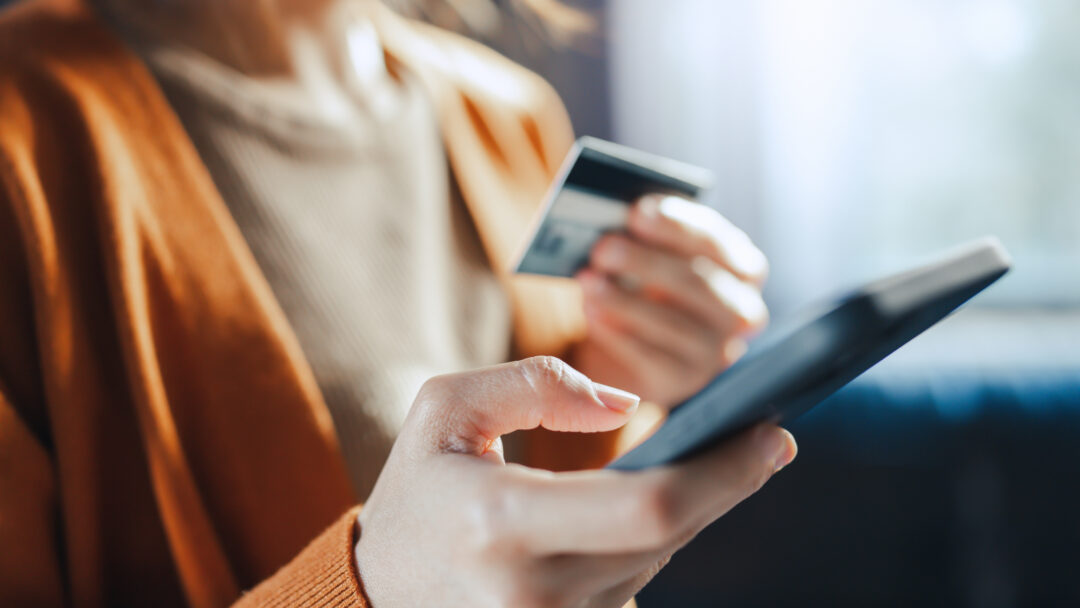 Woman holding a credit card and smartphone while making an online purchase or managing her finances.