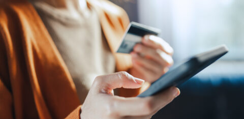 Woman holding a credit card and smartphone while making an online purchase or managing her finances.