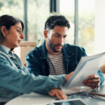 House, documents and couple with laptop, discussion and planning finance with savings. Assets, paperwork and man with woman, pc and expenses with budget, mortgage payment or bills with life insurance