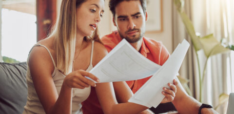 Budget, debt and mortgage with a couple reading bills and documents while checking their expenses and savings. Husband and wife looking worried while reading a loan application or contract together