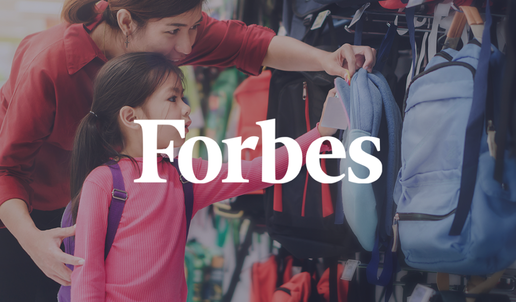 Mother and young daughter shopping for backpacks together during back-to-school season