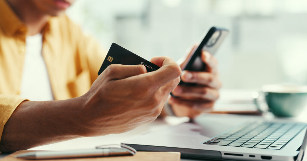 Hands, credit card and laptop at office with phone, online shopping and fintech for easy payment. Person, computer and smartphone with ecommerce, bills or digital bank with customer experience on web