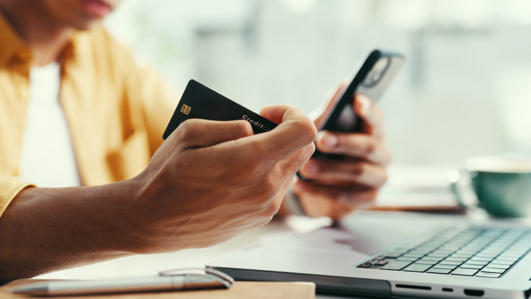 Hands, credit card and laptop at office with phone, online shopping and fintech for easy payment. Person, computer and smartphone with ecommerce, bills or digital bank with customer experience on web