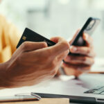 Hands, credit card and laptop at office with phone, online shopping and fintech for easy payment. Person, computer and smartphone with ecommerce, bills or digital bank with customer experience on web