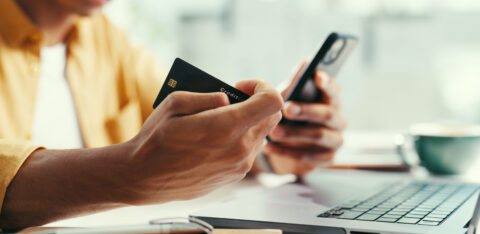 Hands, credit card and laptop at office with phone, online shopping and fintech for easy payment. Person, computer and smartphone with ecommerce, bills or digital bank with customer experience on web