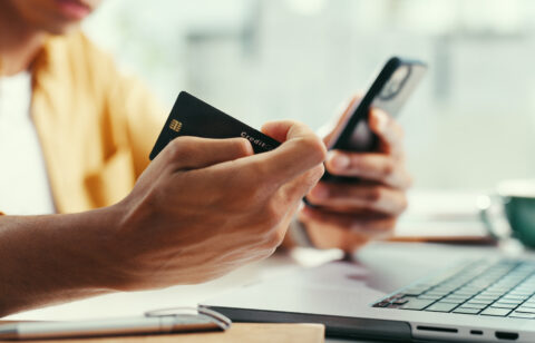 Hands, credit card and laptop at office with phone, online shopping and fintech for easy payment. Person, computer and smartphone with ecommerce, bills or digital bank with customer experience on web
