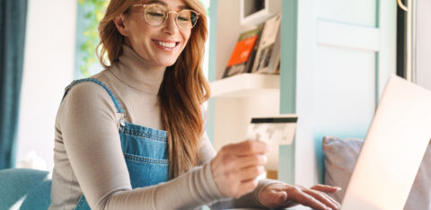 Photo of smiling mature woman holding credit card while using on laptop