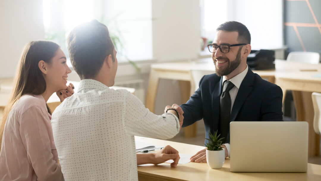 Smiling lawyer or financial advisor handshaking senior couple at