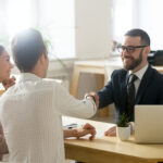 Smiling lawyer or financial advisor handshaking senior couple at