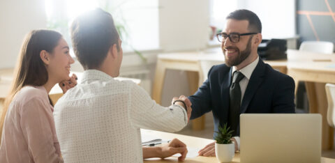 Smiling lawyer or financial advisor handshaking senior couple at