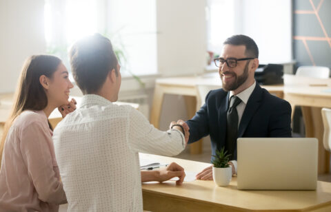 Smiling lawyer or financial advisor handshaking senior couple at