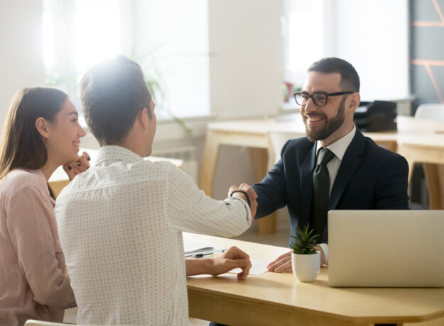 Smiling lawyer or financial advisor handshaking senior couple at