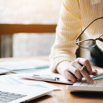 Close up Business woman using calculator and laptop for do math