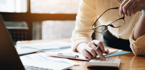 Close up Business woman using calculator and laptop for do math