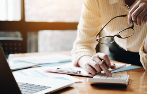 Close up Business woman using calculator and laptop for do math
