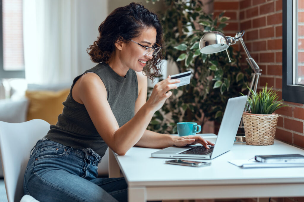 Cute woman holding white credit card for shopping online with co