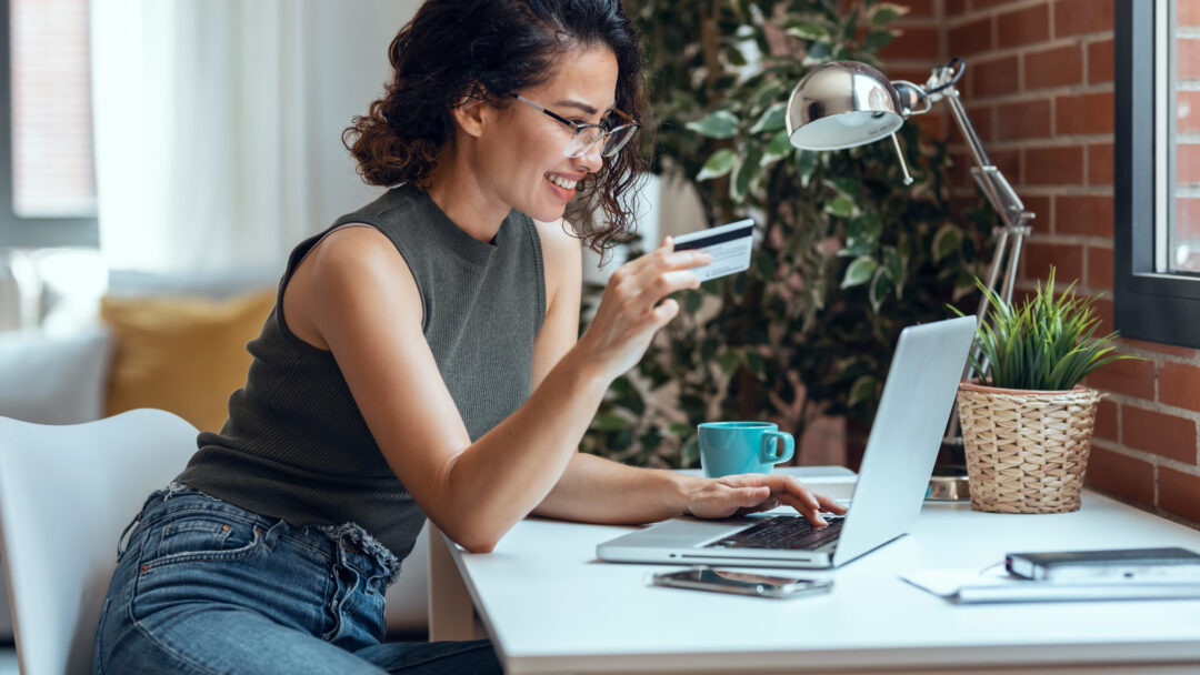 Cute woman holding white credit card for shopping online with co