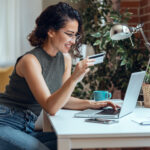 Cute woman holding white credit card for shopping online with co