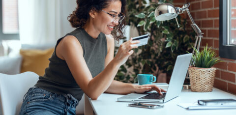 Cute woman holding white credit card for shopping online with co
