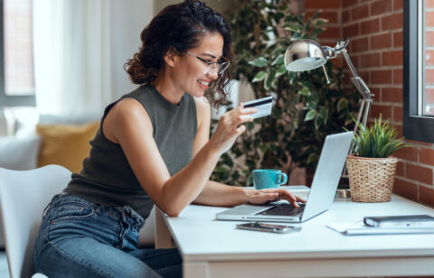 Cute woman holding white credit card for shopping online with co