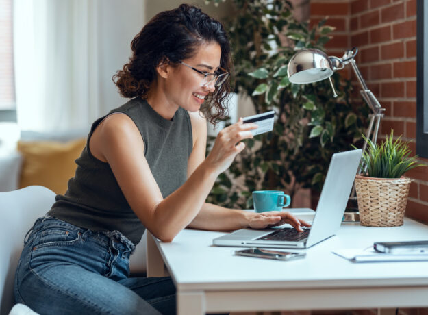 Cute woman holding white credit card for shopping online with co