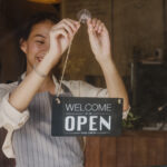 Young Asia manager girl changing a sign from closed to open sign