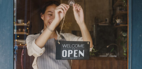 Young Asia manager girl changing a sign from closed to open sign