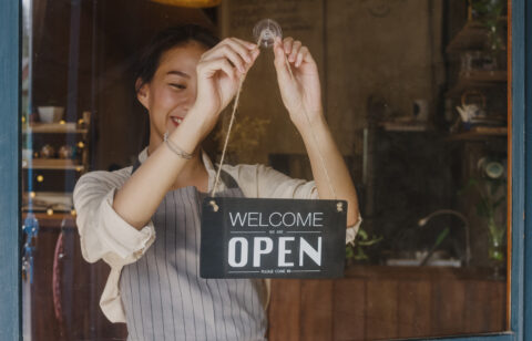 Young Asia manager girl changing a sign from closed to open sign