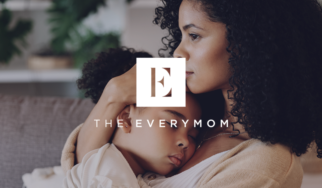 Mom holding her young daughter with The Everymom logo layered on top.