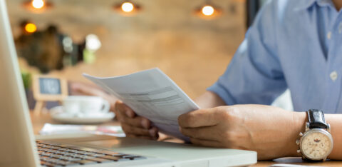 Businessman using laptop while looking at invoice.