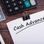 Cash advance text on white paper with calculator and US dollar