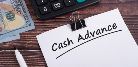 Cash advance text on white paper with calculator and US dollar