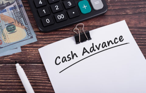 Cash advance text on white paper with calculator and US dollar