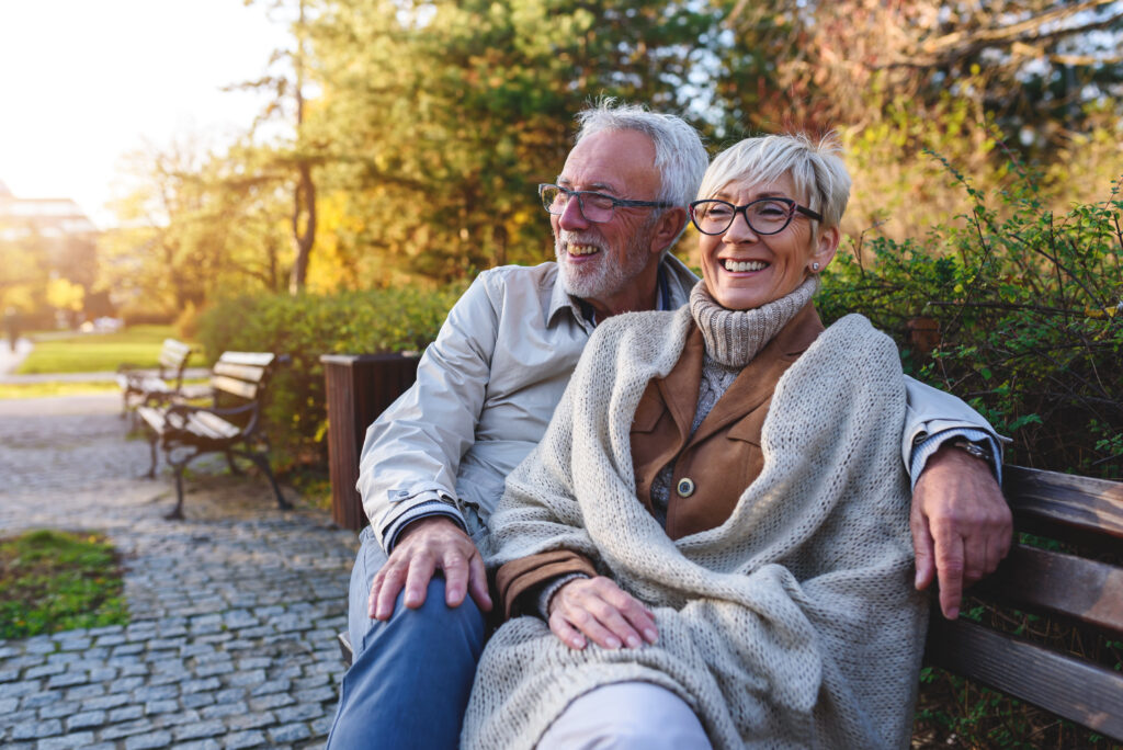 Smiling senior couple sitting on the bench in the park together