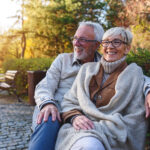 Smiling senior couple sitting on the bench in the park together