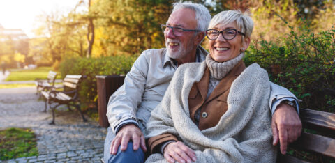 Smiling senior couple sitting on the bench in the park together