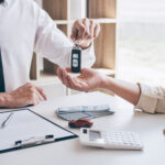 Agent holding key of new car giving to woman client after signing contract